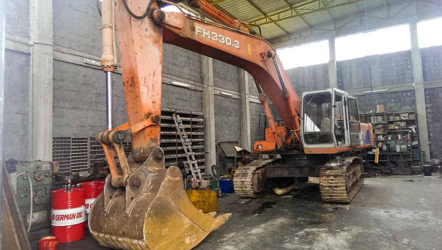 Ekskavator portokalli pranë një ndërtese në ndërtim